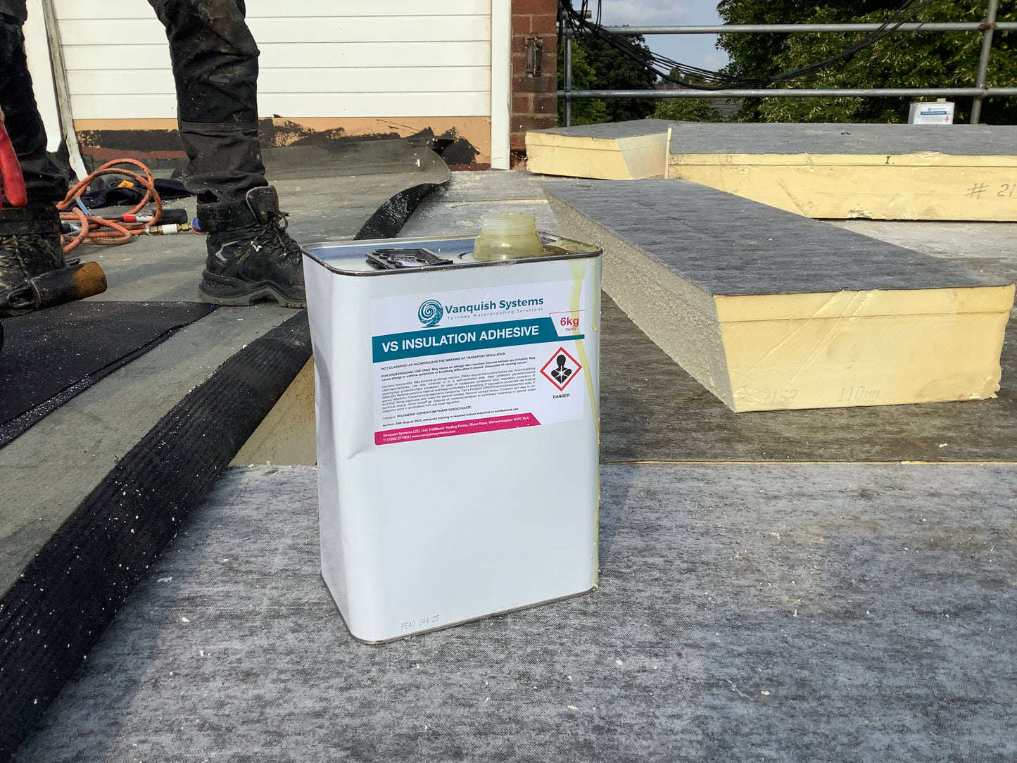 Can of insulation adhesive on a roof with insulation material in the background