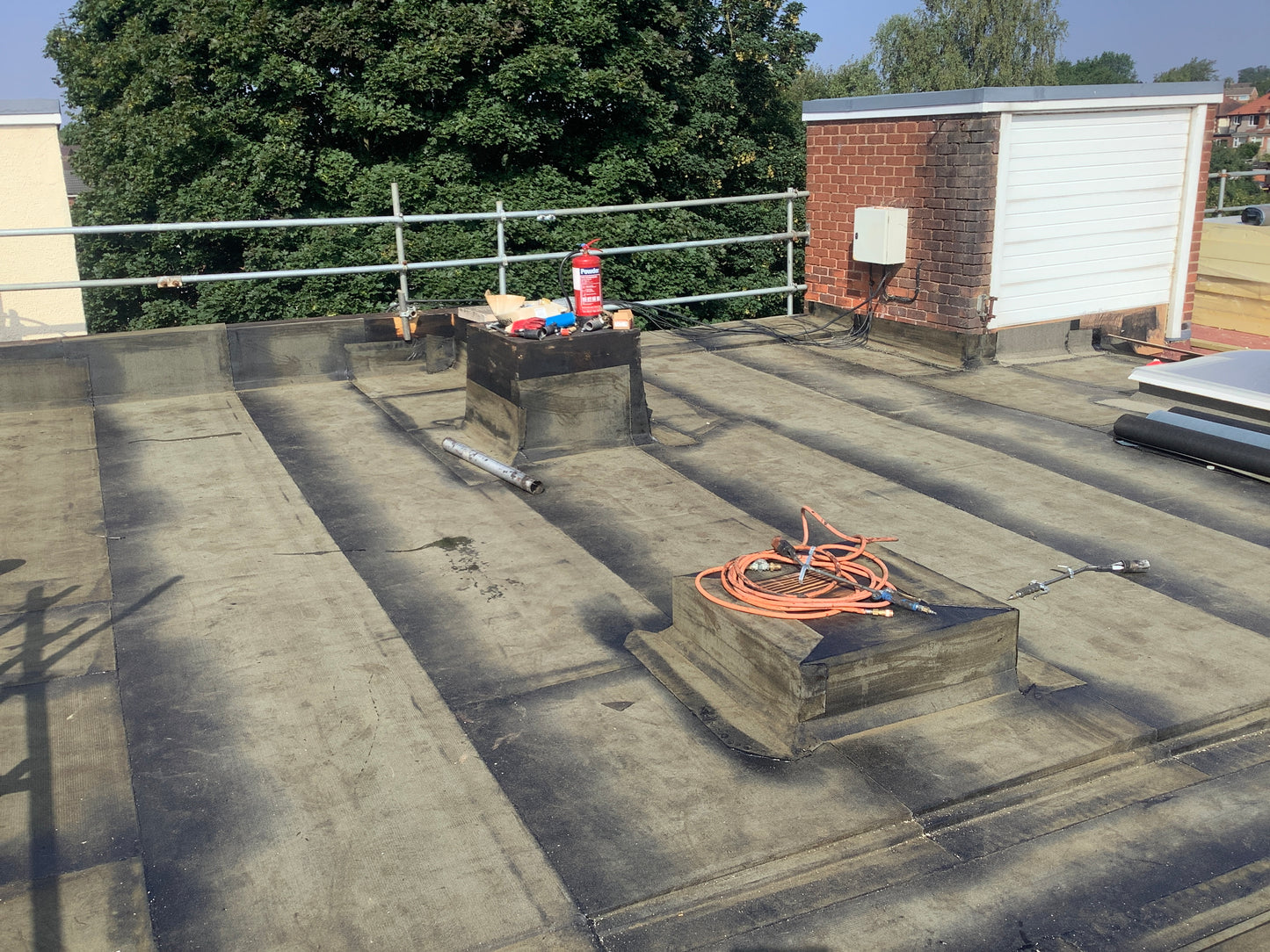 Roofing work in progress on a building with tools and materials.