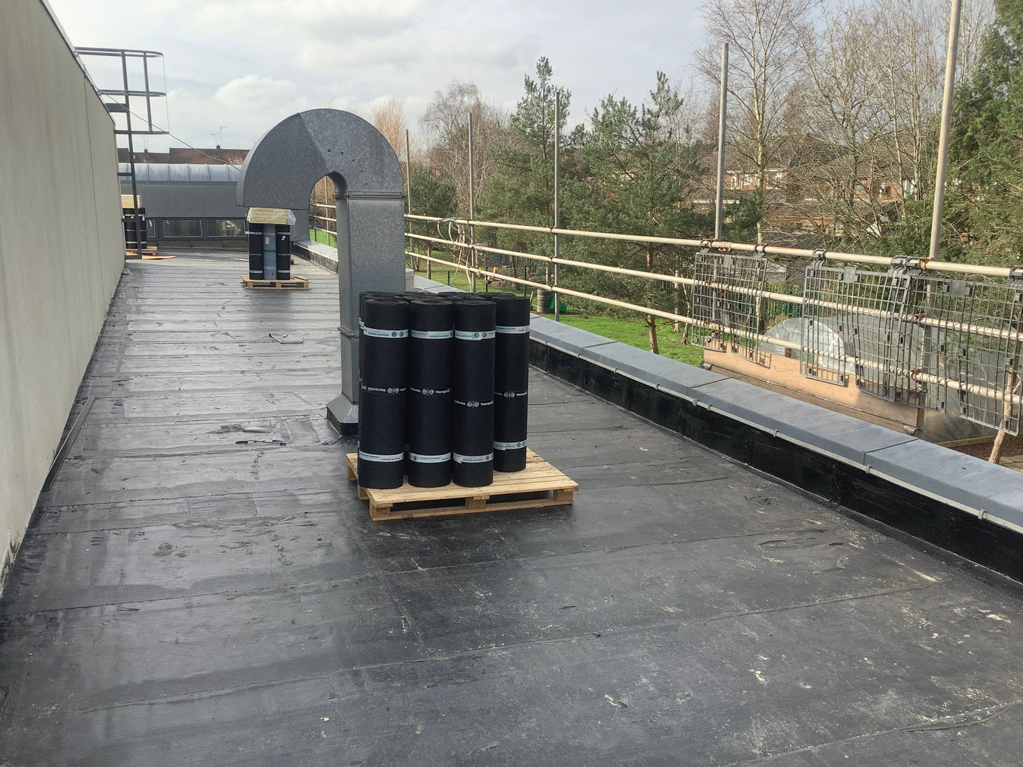 Torch-applied roofing membrane rolls positioned on a commercial flat roof project